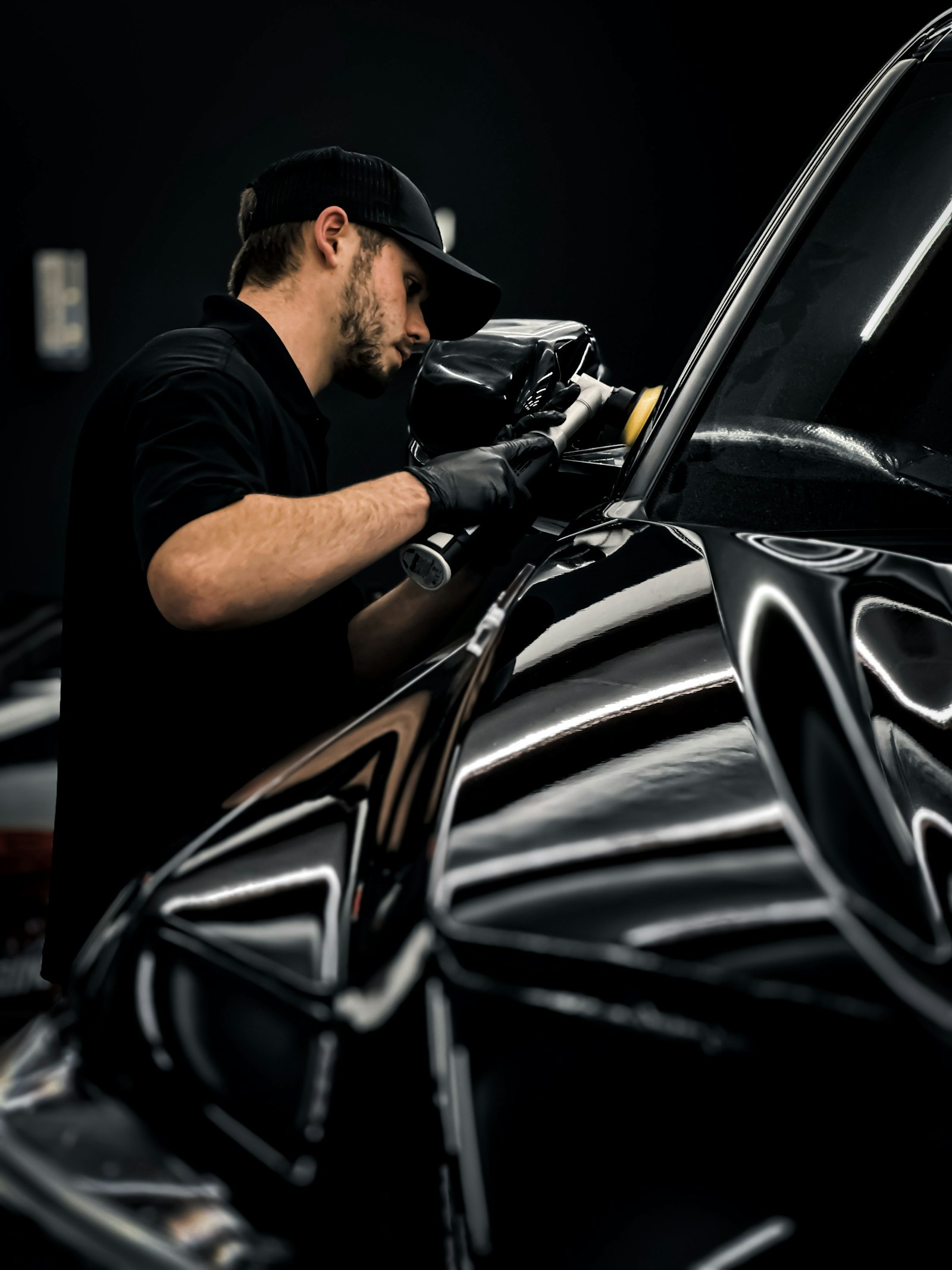 Technicien polissant la carrosserie d’une voiture noire en atelier